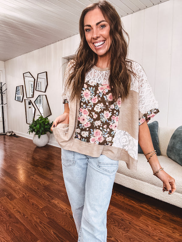 Lightweight ribbed textured taupe top with lace at the yoke and sides and a brown and pink and blue floral patch in the front at at the cuffs of the short sleeves. Oversized.