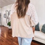Lightweight ribbed textured taupe top with lace at the yoke and sides and a brown and pink and blue floral patch in the front at at the cuffs of the short sleeves. Oversized.