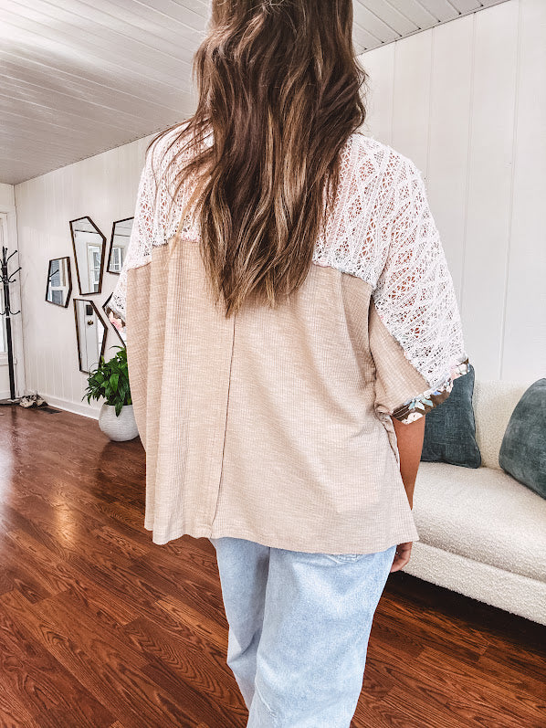 Lightweight ribbed textured taupe top with lace at the yoke and sides and a brown and pink and blue floral patch in the front at at the cuffs of the short sleeves. Oversized.
