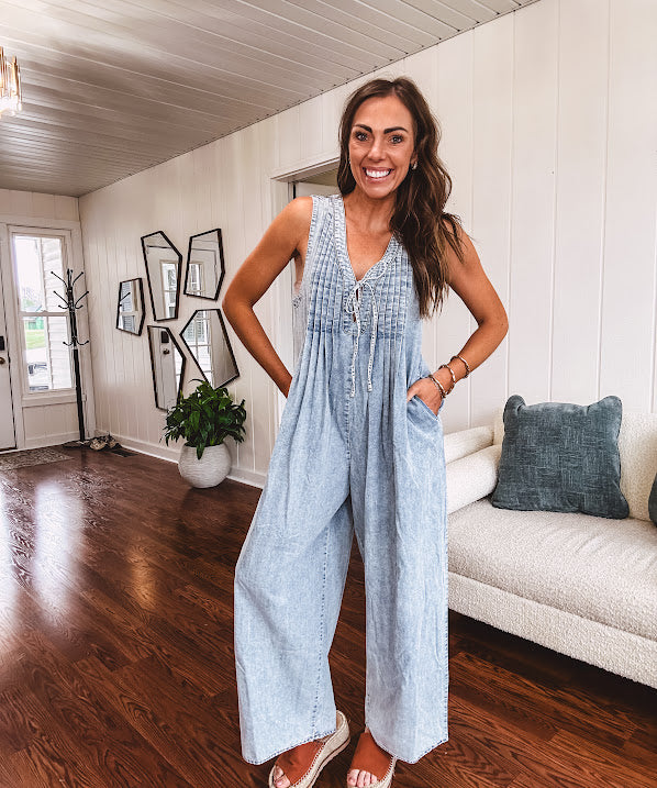 Light wash, lightweight denim jumpsuit with pintuck detail at the top, tie V neck, wide leg design and pockets.