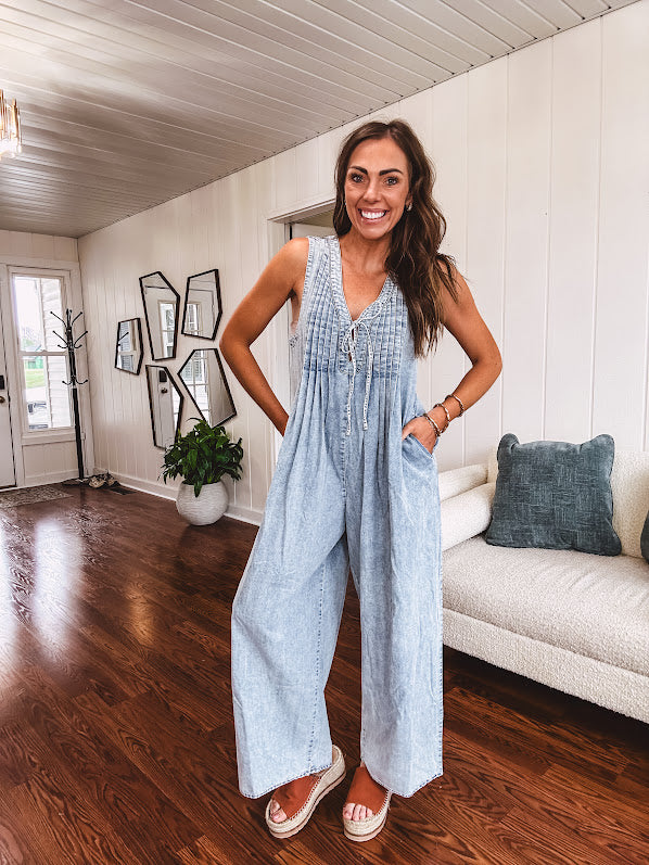 Light wash, lightweight denim jumpsuit with pintuck detail at the top, tie V neck, wide leg design and pockets.