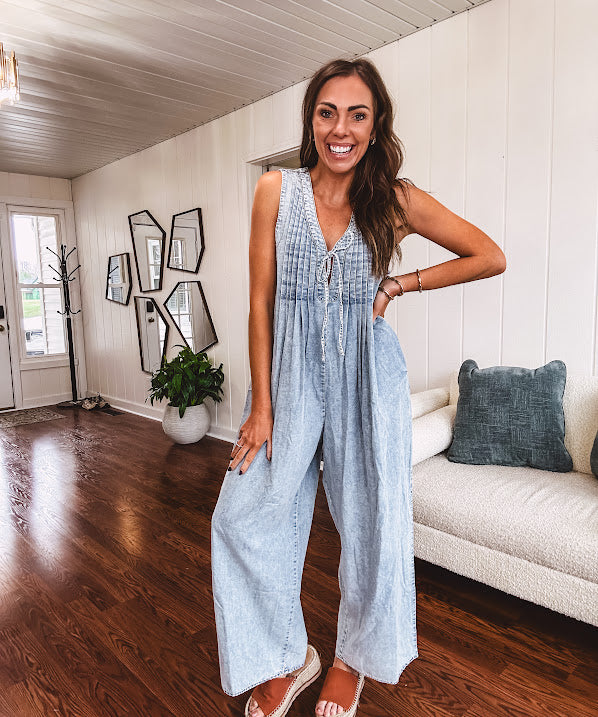 Light wash, lightweight denim jumpsuit with pintuck detail at the top, tie V neck, wide leg design and pockets.
