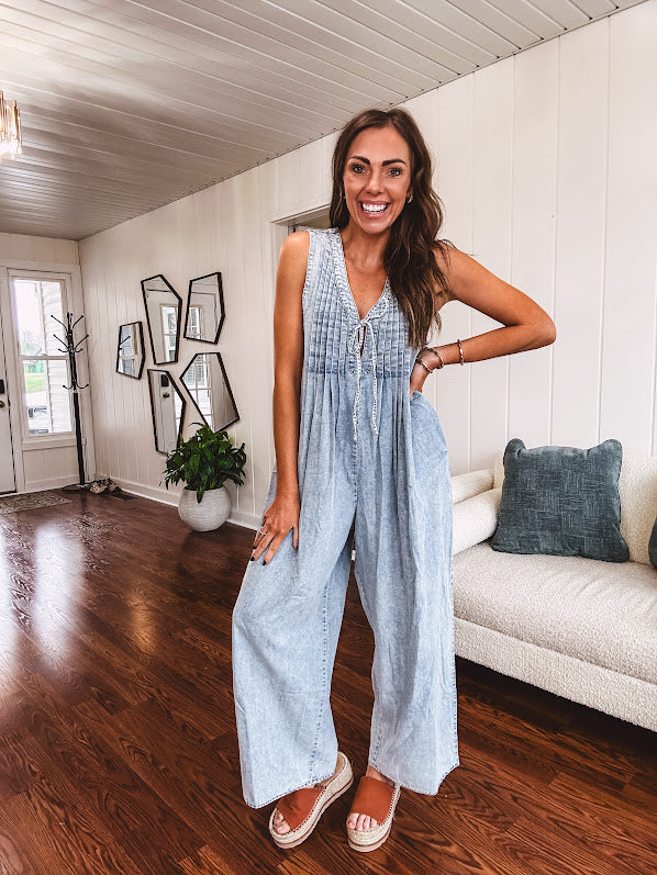 Light wash, lightweight denim jumpsuit with pintuck detail at the top, tie V neck, wide leg design and pockets.
