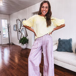 Light purple denim-like wide leg pants with elastic back waist, button and zipper closure and pleating at the front, with pockets and small pink and yellow florals throughout.
