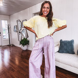 Light purple denim-like wide leg pants with elastic back waist, button and zipper closure and pleating at the front, with pockets and small pink and yellow florals throughout.