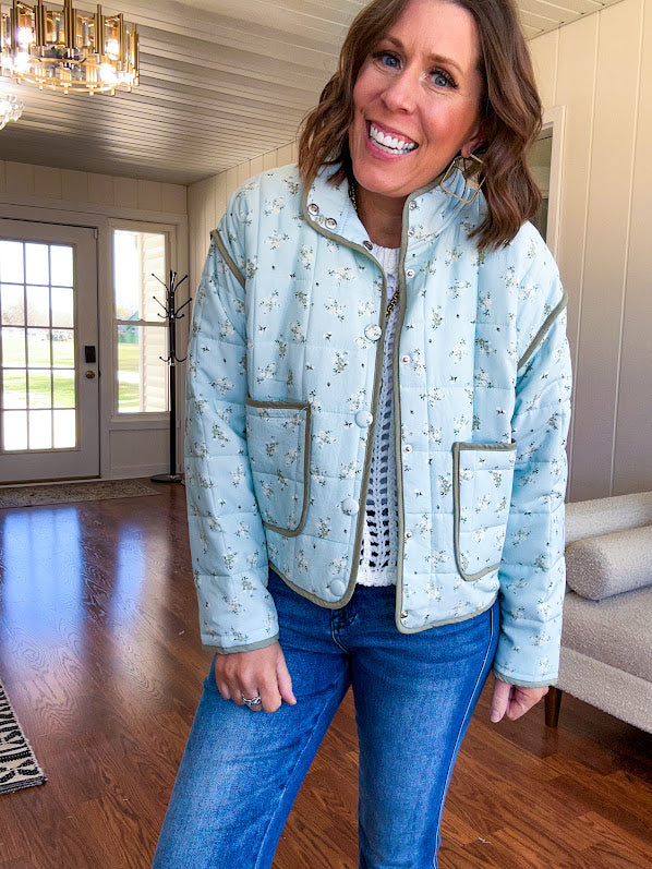 Mint green light weight quilted jacket with olive and white mini florals throughout and olive trim with snap button front and pockets.