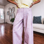 Light purple denim-like wide leg pants with elastic back waist, button and zipper closure and pleating at the front, with pockets and small pink and yellow florals throughout.