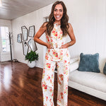 Fitted cream snap front vest with bright coral florals and blue accents with pockets.