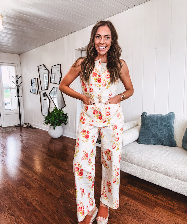 Fitted cream snap front vest with bright coral florals and blue accents with pockets.
