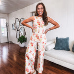 Fitted cream snap front vest with bright coral florals and blue accents with pockets.