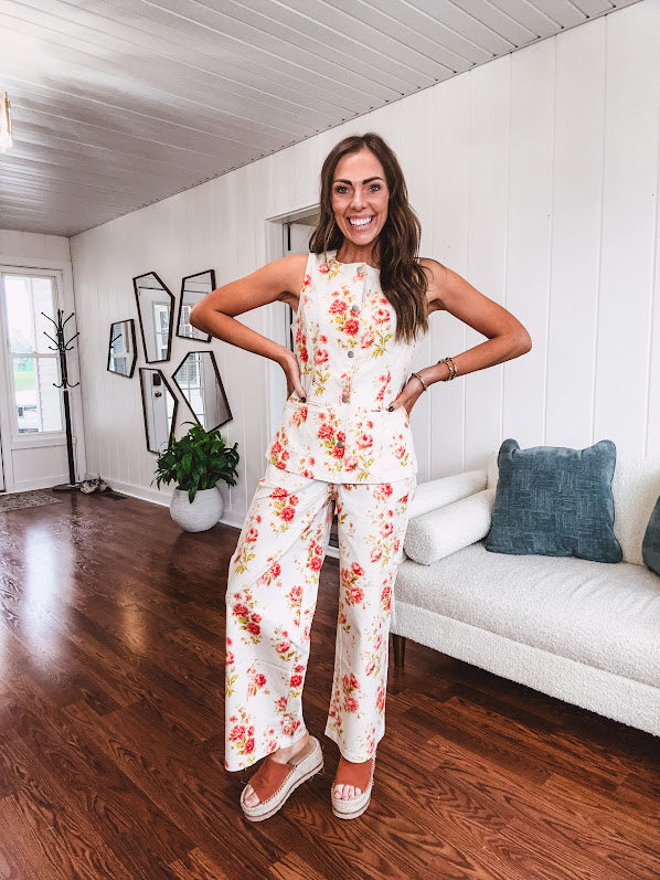 Fitted cream snap front vest with bright coral florals and blue accents with pockets.