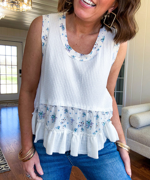 Lightweight ribbed textured white tank with blue floral trim and ruffled hem.