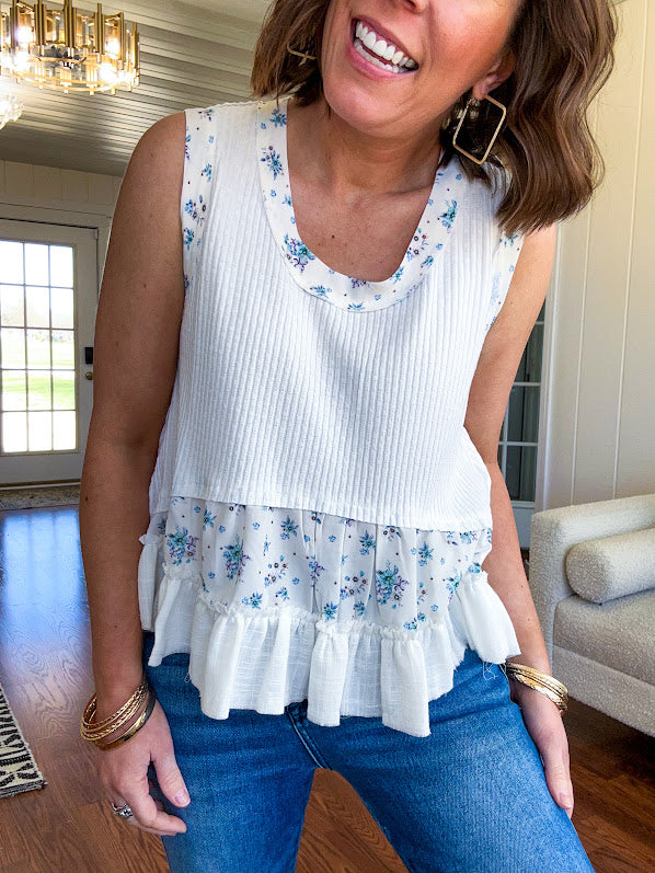 Lightweight ribbed textured white tank with blue floral trim and ruffled hem.