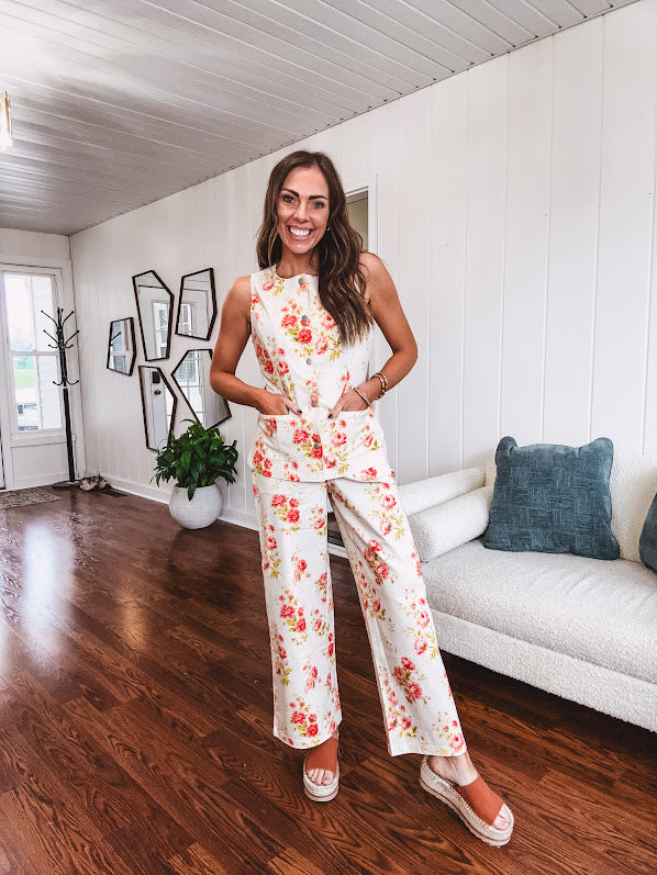 Cream wide leg pants with elastic back and button zipper front with bold coral and green florals throughout with blue accents, front and back pockets.