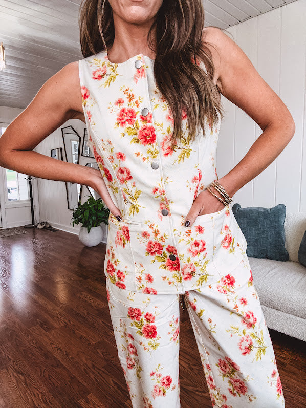 Fitted cream snap front vest with bright coral florals and blue accents with pockets.