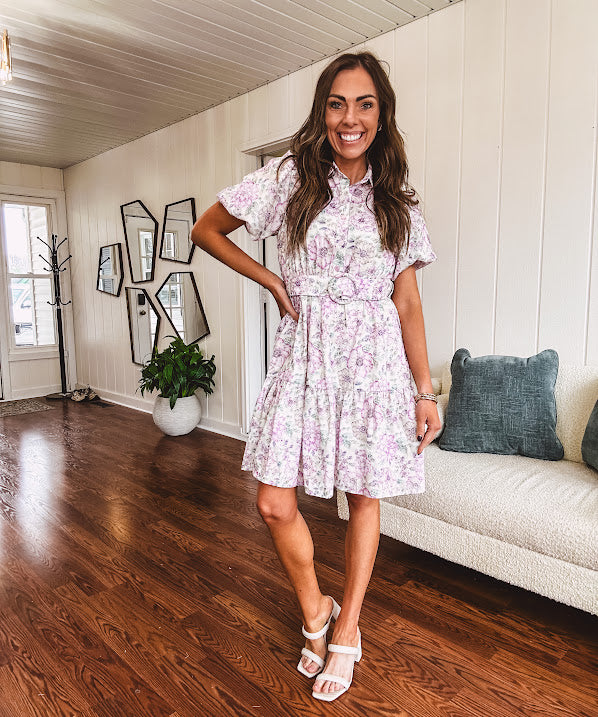 Fully lined , short lavender multi floral shirt dress with elastic waist, matching fabric belt, puff sleeves and tiered skirt.