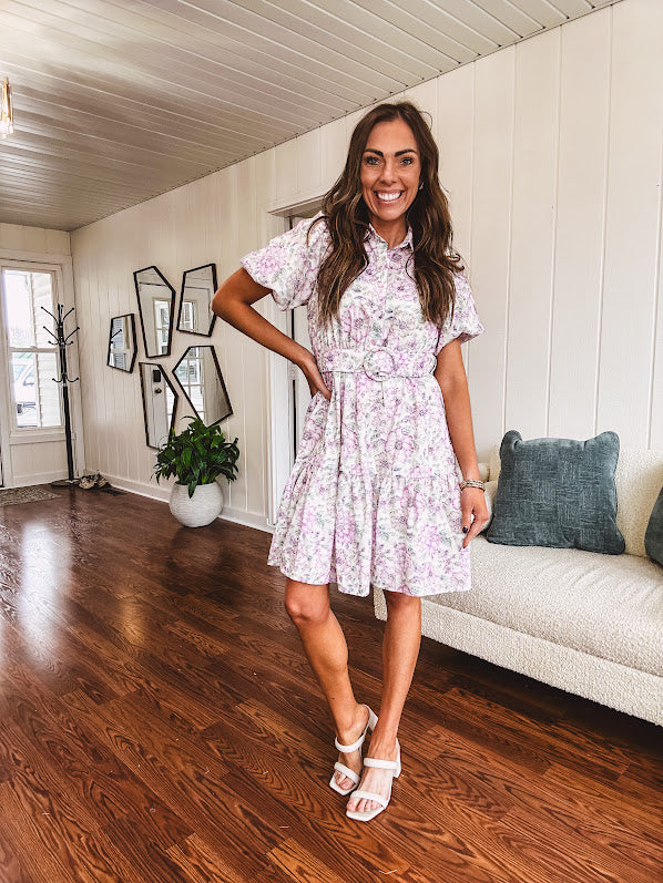 Fully lined , short lavender multi floral shirt dress with elastic waist, matching fabric belt, puff sleeves and tiered skirt.
