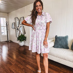 Fully lined , short lavender multi floral shirt dress with elastic waist, matching fabric belt, puff sleeves and tiered skirt.