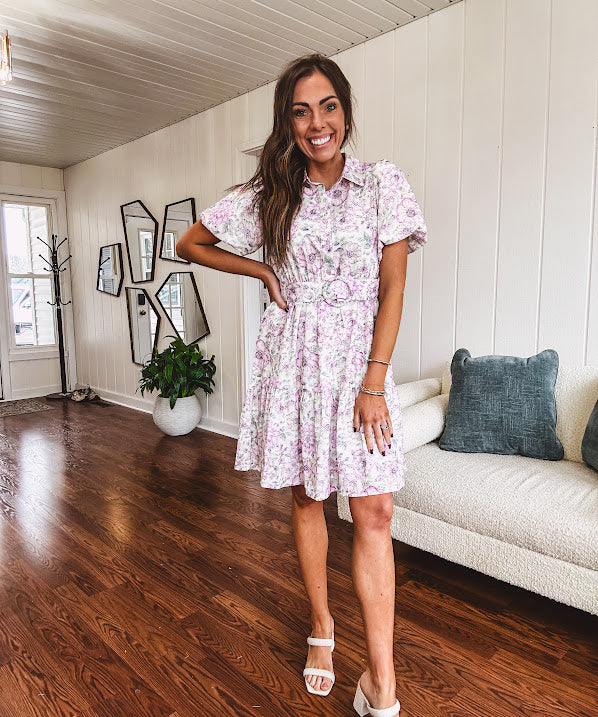 Fully lined , short lavender multi floral shirt dress with elastic waist, matching fabric belt, puff sleeves and tiered skirt.