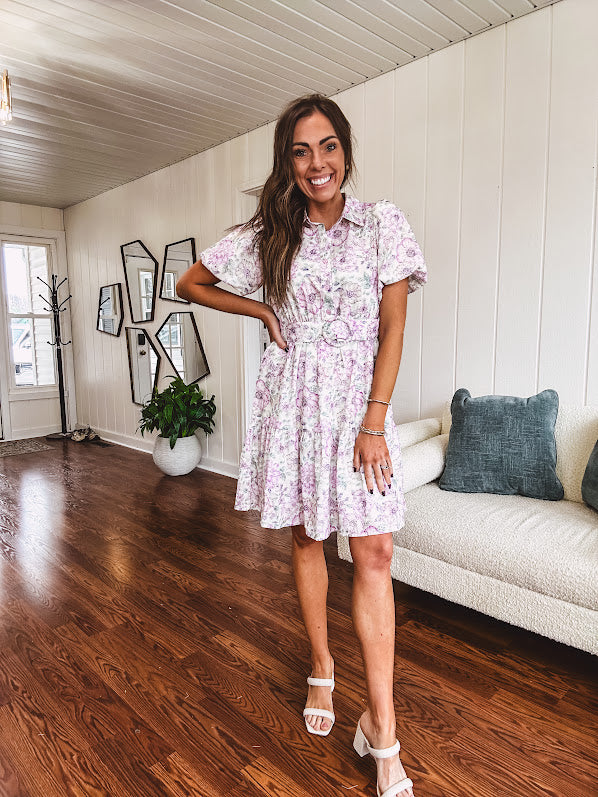 Fully lined , short lavender multi floral shirt dress with elastic waist, matching fabric belt, puff sleeves and tiered skirt.
