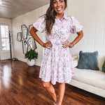 Fully lined , short lavender multi floral shirt dress with elastic waist, matching fabric belt, puff sleeves and tiered skirt.