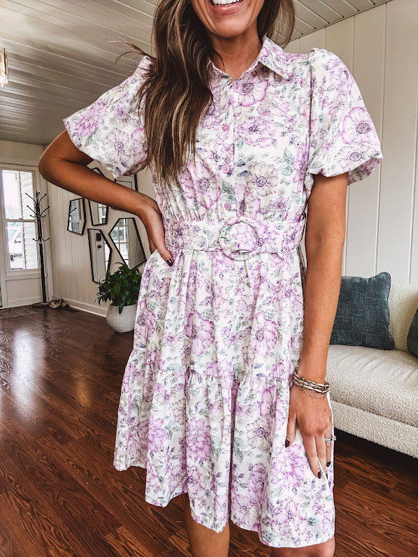Fully lined , short lavender multi floral shirt dress with elastic waist, matching fabric belt, puff sleeves and tiered skirt.