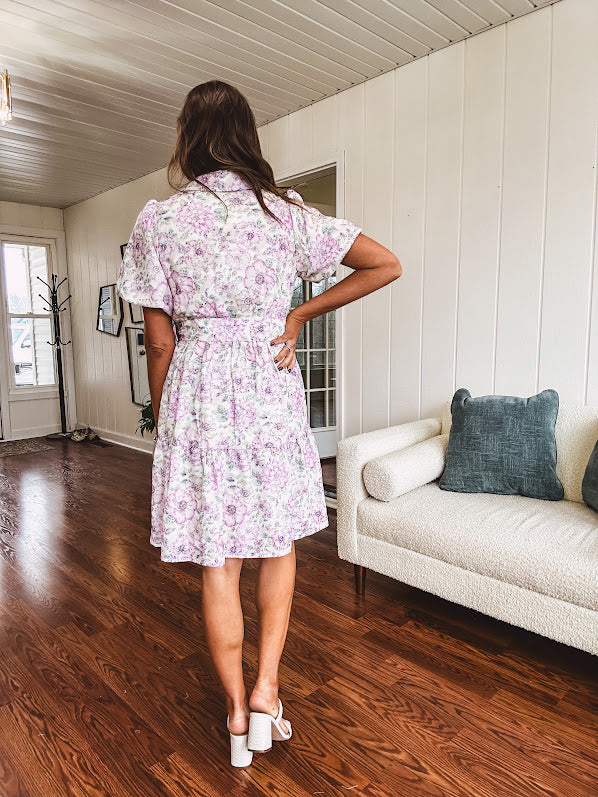 Fully lined , short lavender multi floral shirt dress with elastic waist, matching fabric belt, puff sleeves and tiered skirt.