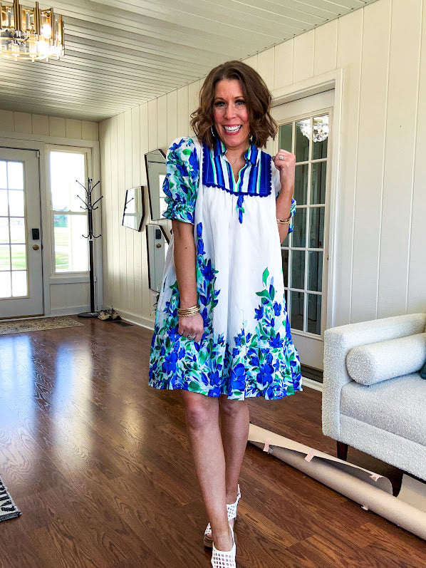 Fully lined linen-like short white dress with royal blue, lime green and purple stripes at the yoke and florals throughout with rickrack trim at the yoke and collar with V neck. Has pockets.