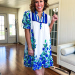 Fully lined linen-like short white dress with royal blue, lime green and purple stripes at the yoke and florals throughout with rickrack trim at the yoke and collar with V neck. Has pockets.