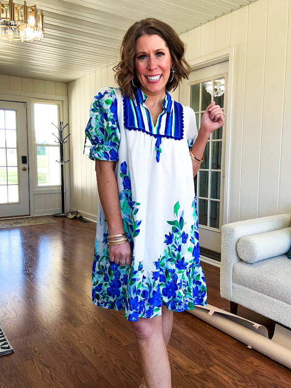 Fully lined linen-like short white dress with royal blue, lime green and purple stripes at the yoke and florals throughout with rickrack trim at the yoke and collar with V neck. Has pockets.