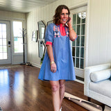 Slate blue dress with puffed, cuffed short sleeves, pockets, a contrasting coral collar and V neck, cuffs and trim and coral and pink embroidery at the yoke.