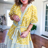 Fully lined short sleeved short dress with mustard polka dots trimmed in dusty blue, mustard and cream stripes at the mock neck and placket, ruffled cuffs, belt and hem.