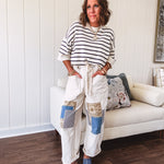 Creamy wide-leg pants, denim-like cotton material with silver grommet belt loops and a coordinating rope belt, button fly and oversized pockets, and striped patchwork in sand, denim, navy, and white creates visual interest down the legs.