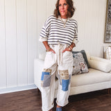 Creamy wide-leg pants, denim-like cotton material with silver grommet belt loops and a coordinating rope belt, button fly and oversized pockets, and striped patchwork in sand, denim, navy, and white creates visual interest down the legs.