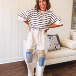 Creamy wide-leg pants, denim-like cotton material with silver grommet belt loops and a coordinating rope belt, button fly and oversized pockets, and striped patchwork in sand, denim, navy, and white creates visual interest down the legs.