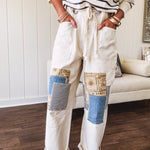 Creamy wide-leg pants, denim-like cotton material with silver grommet belt loops and a coordinating rope belt, button fly and oversized pockets, and striped patchwork in sand, denim, navy, and white creates visual interest down the legs.