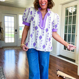 Fully lined lavender and cream blouse with lavender trim at the mock collar and V neck and cuffs, short puffed sleeves and lavender and cream embroidery throughout in an abstract pattern.