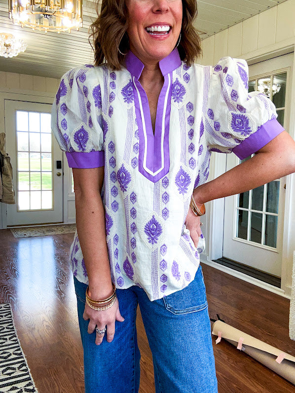 Fully lined lavender and cream blouse with lavender trim at the mock collar and V neck and cuffs, short puffed sleeves and lavender and cream embroidery throughout in an abstract pattern.