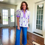 Fully lined lavender and cream blouse with lavender trim at the mock collar and V neck and cuffs, short puffed sleeves and lavender and cream embroidery throughout in an abstract pattern.