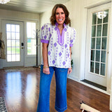 Fully lined lavender and cream blouse with lavender trim at the mock collar and V neck and cuffs, short puffed sleeves and lavender and cream embroidery throughout in an abstract pattern.