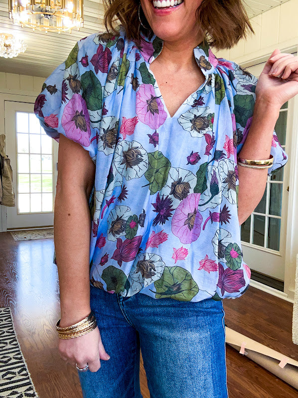 Lined blue flowy bubble hem blouse with mock collar and V neck and bubble short sleeves with purple, sage, olive and pink florals throughout.