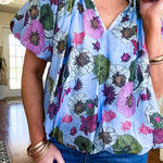 Lined blue flowy bubble hem blouse with mock collar and V neck and bubble short sleeves with purple, sage, olive and pink florals throughout.