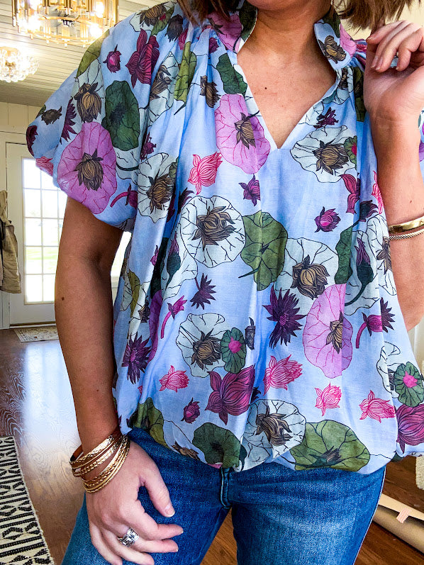 Lined blue flowy bubble hem blouse with mock collar and V neck and bubble short sleeves with purple, sage, olive and pink florals throughout.
