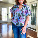 Lined blue flowy bubble hem blouse with mock collar and V neck and bubble short sleeves with purple, sage, olive and pink florals throughout.