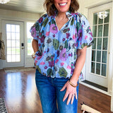 Lined blue flowy bubble hem blouse with mock collar and V neck and bubble short sleeves with purple, sage, olive and pink florals throughout.