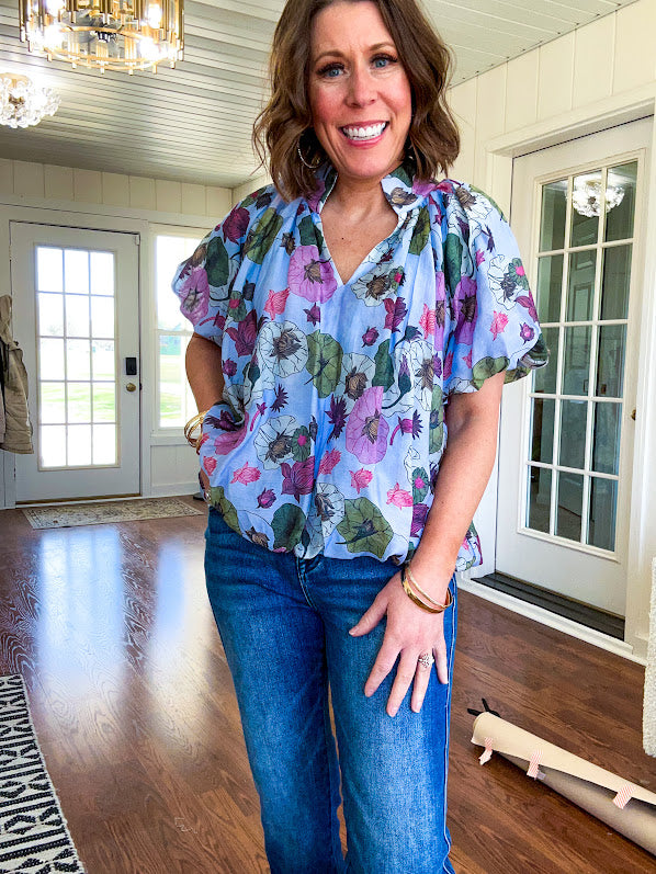 Lined blue flowy bubble hem blouse with mock collar and V neck and bubble short sleeves with purple, sage, olive and pink florals throughout.
