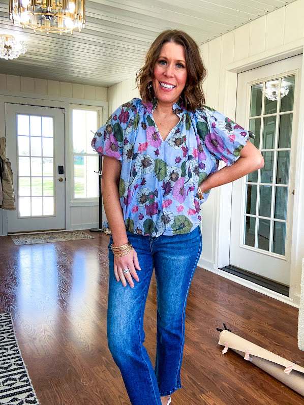 Lined blue flowy bubble hem blouse with mock collar and V neck and bubble short sleeves with purple, sage, olive and pink florals throughout.