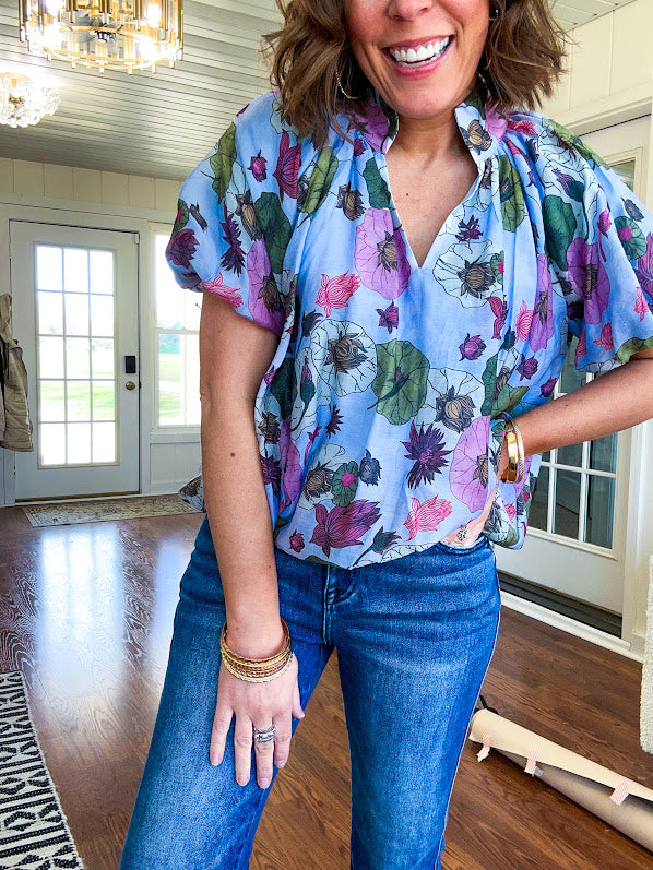 Lined blue flowy bubble hem blouse with mock collar and V neck and bubble short sleeves with purple, sage, olive and pink florals throughout.