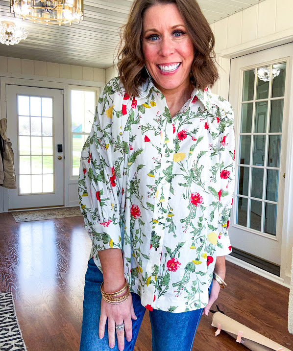 Cream 3/4 sleeve button down top with collar and pleating at the yoke with red, yellow and green florals throughout.
