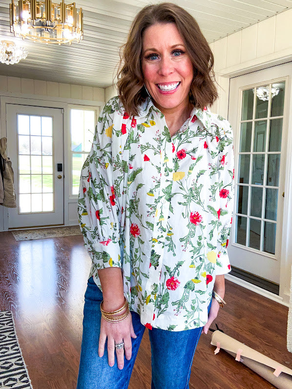 Cream 3/4 sleeve button down top with collar and pleating at the yoke with red, yellow and green florals throughout.